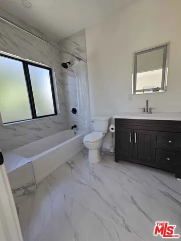 a bathroom with a granite countertop toilet a sink and a bathtub