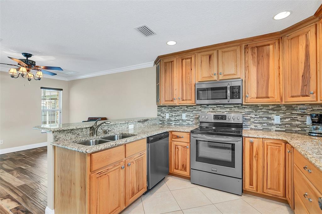 4147 Boggy Creek Road Kissimmee, FL 34744 - Photo 29 of 49 a kitchen with stainless steel appliances granite countertop a sink stove and microwave