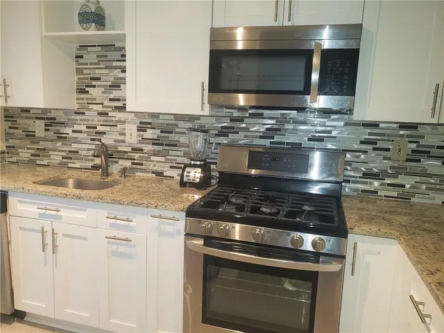 a kitchen with stainless steel appliances granite countertop a stove microwave and sink