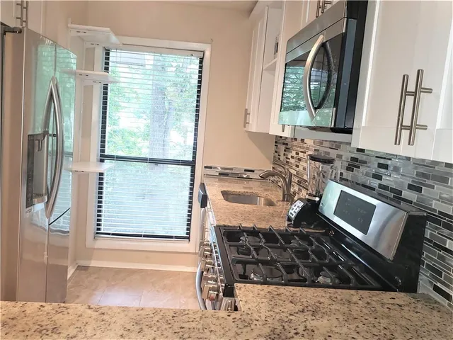 a kitchen with stainless steel appliances granite countertop a refrigerator and a sink