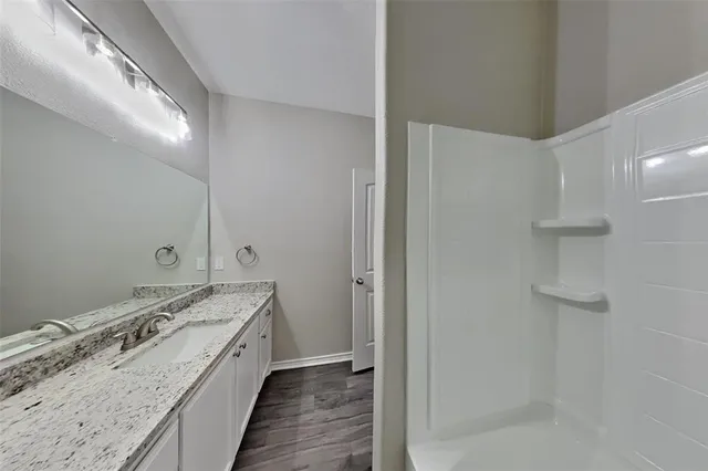 a bathroom with a granite countertop sink a vanity and shower