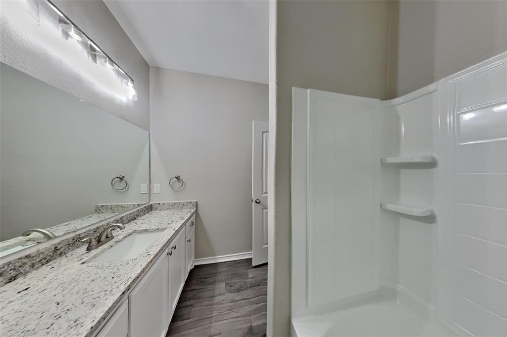 6285 Spring Buck Run Fort Worth, TX 76179 - Photo 15 of 18 a bathroom with a granite countertop sink a vanity and shower
