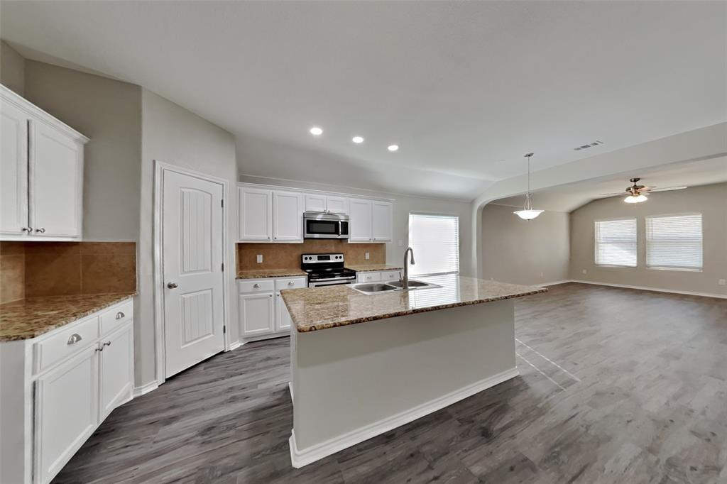 6285 Spring Buck Run Fort Worth, TX 76179 - Photo 4 of 18 a large white kitchen with stainless steel appliances granite countertop a stove a sink a refrigerator white cabinets and wooden floor