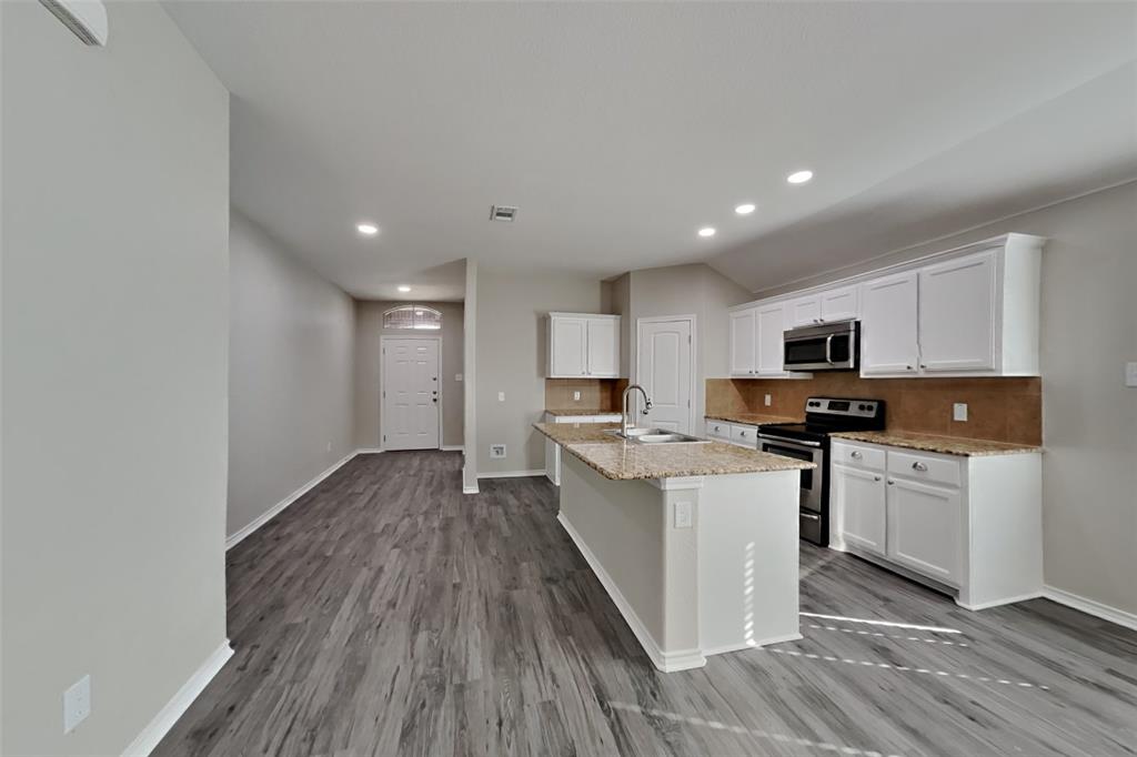 6285 Spring Buck Run Fort Worth, TX 76179 - Photo 5 of 18 a kitchen with stainless steel appliances granite countertop a stove top oven a sink a refrigerator with white cabinets and wooden floor