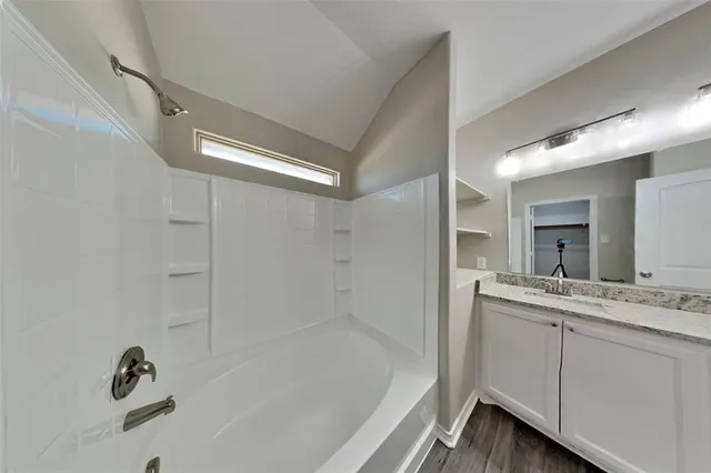 a bathroom with a tub sink and mirror