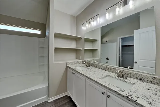 a bathroom with a granite countertop sink a large mirror and a bathtub