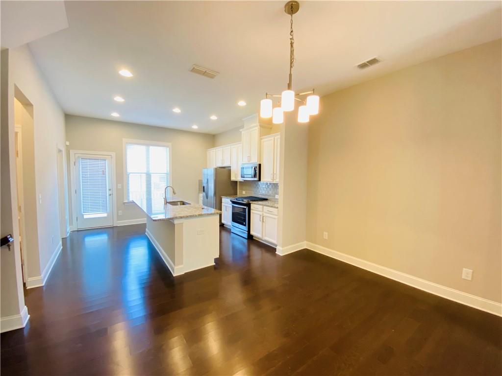 1815 Hislop Lane, Unit 8 Atlanta, GA 30345 - Photo 6 of 38 a view of a kitchen with kitchen island stainless steel appliances wooden floor and a view of living room