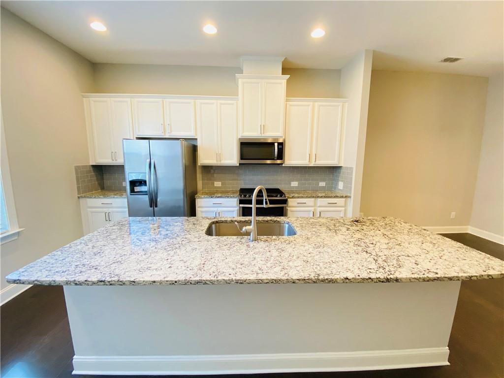 1815 Hislop Lane, Unit 8 Atlanta, GA 30345 - Photo 8 of 38 a kitchen with kitchen island granite countertop a sink a stove a refrigerator and a counter top space