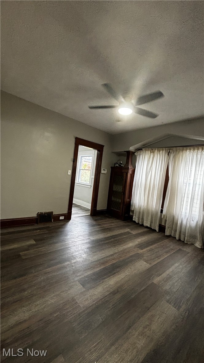13421 Ashburton Road Cleveland, OH 44110 - Photo 9 of 28 Spare room featuring ceiling fan, a textured ceiling, and dark hardwood / wood-style floors