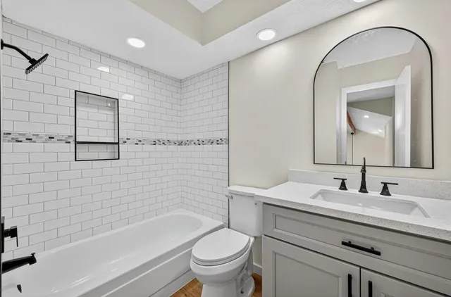 a bathroom with a toilet a sink a mirror and bathtub