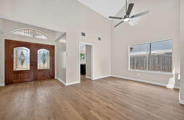 a view of an empty room with wooden floor and a window