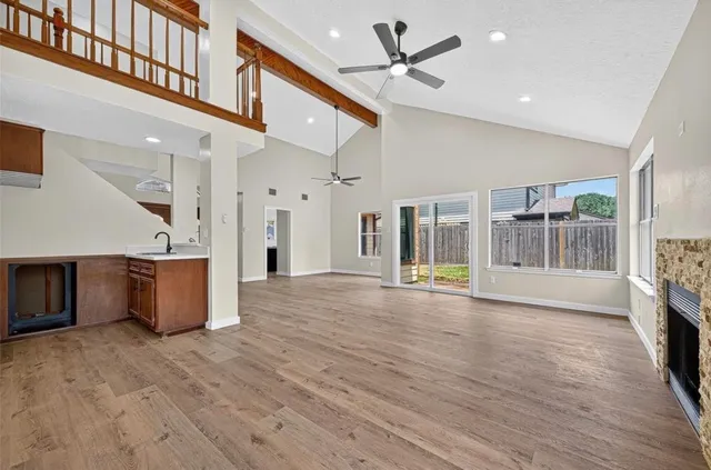 a view of an empty room with wooden floor and a fireplace
