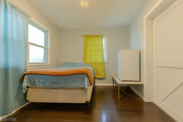 a living room with a bed and wooden floor
