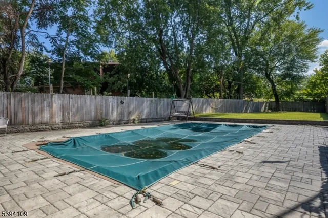 a view of a backyard with large trees and wooden fence