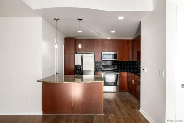 a kitchen with stainless steel appliances granite countertop a sink a stove and a refrigerator