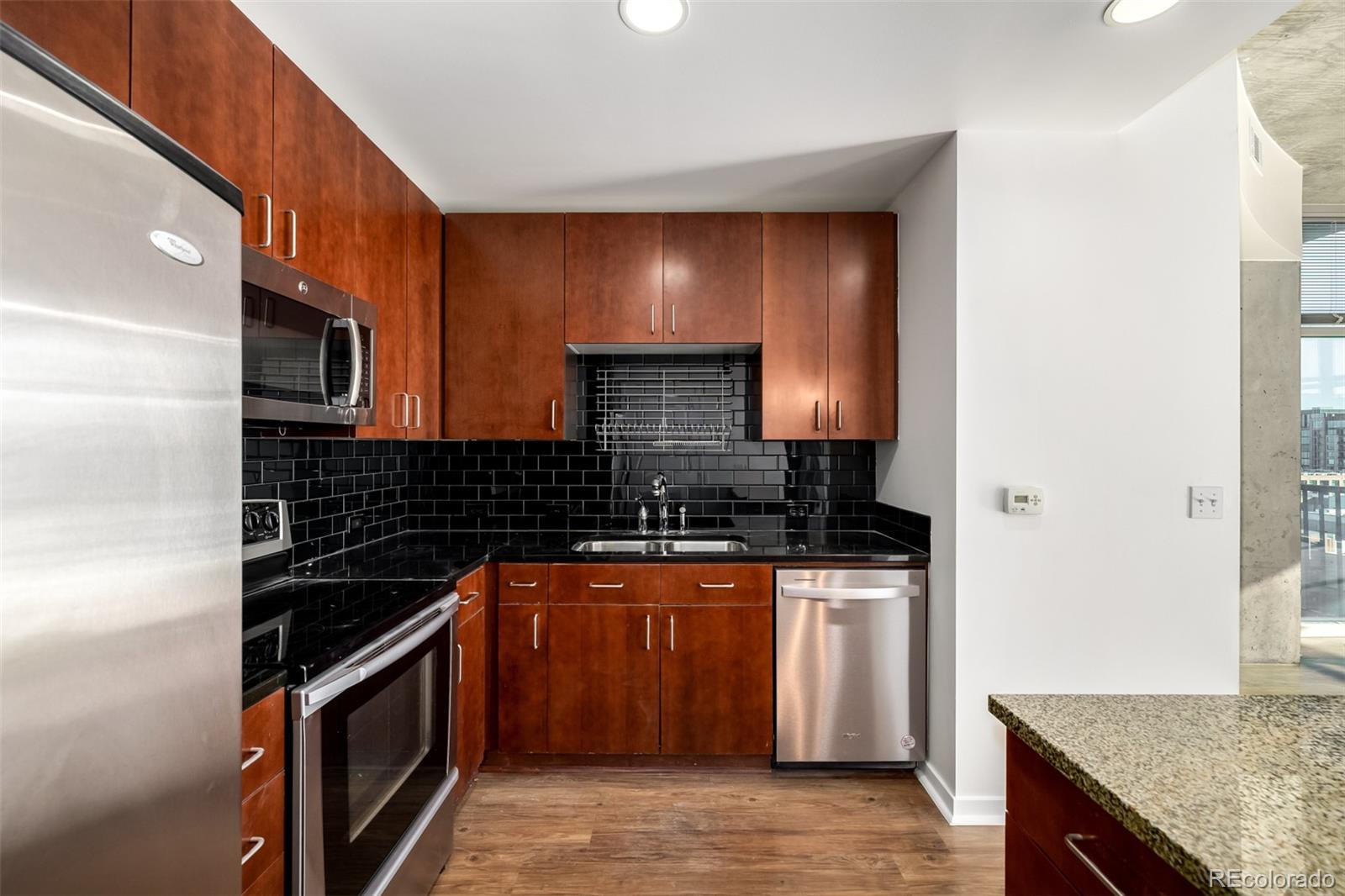 1700 Bassett Street, Unit 1012 Denver, CO 80202 - Photo 19 of 48 a kitchen with stainless steel appliances granite countertop a stove a sink and a microwave