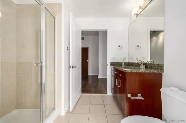 a bathroom with a granite countertop sink a toilet and shower