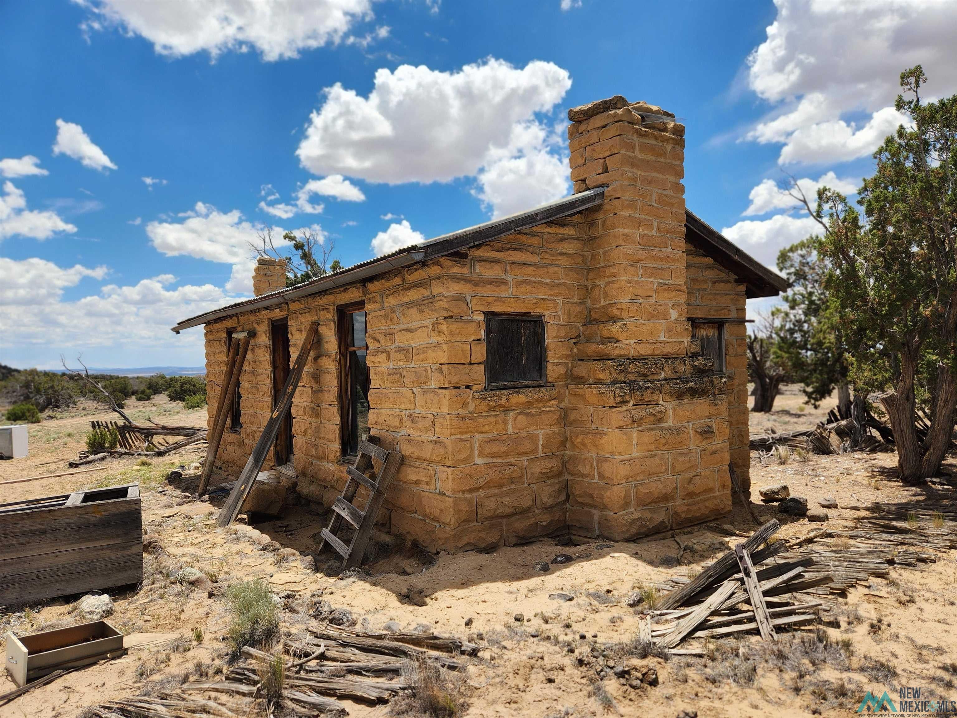 31 Henderson Road Quemado, NM 87829 - Photo 26 of 35 Stone-clad structure featuring a prominent exterior chimney and a sloped roof