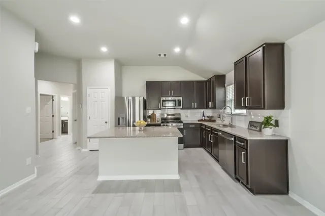 a large kitchen with stainless steel appliances lots of counter space and wooden floor