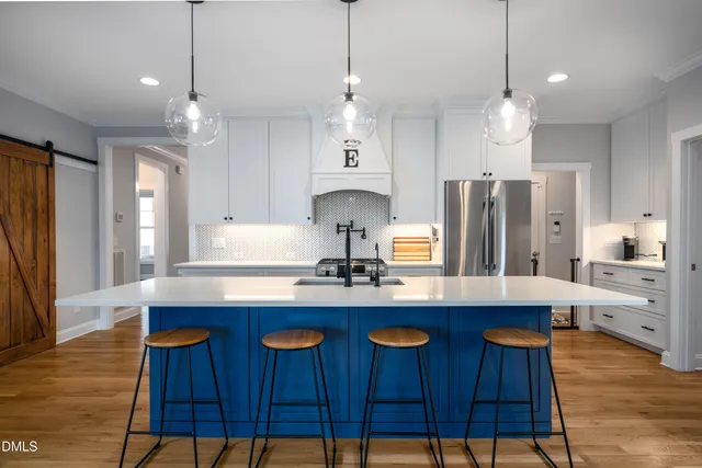 a kitchen with stainless steel appliances a dining table chairs sink and refrigerator