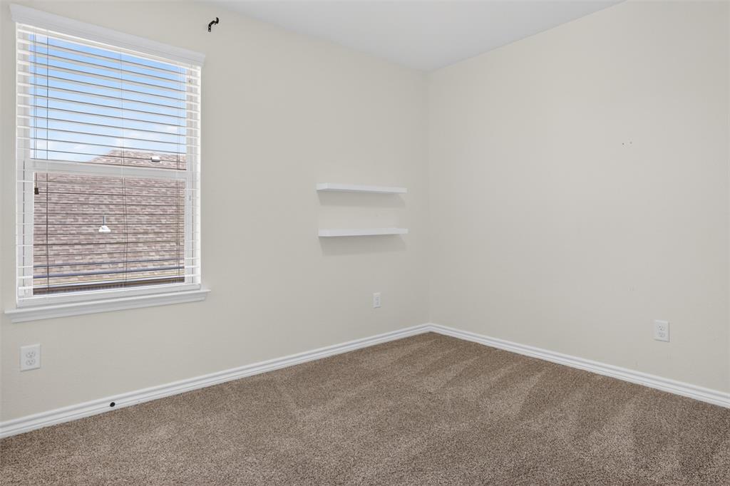 8728 Maple Ridge Trail Fort Worth, TX 76244 - Photo 29 of 40 Neutral-toned room featuring a single window with blinds, light-colored walls, two built-in floating shelves, and carpet flooring
