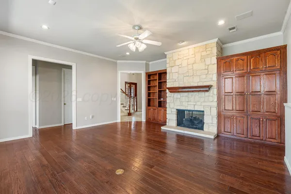an empty room with wooden floor fireplace and windows
