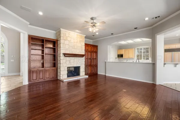 an empty room with wooden floor fireplace and windows
