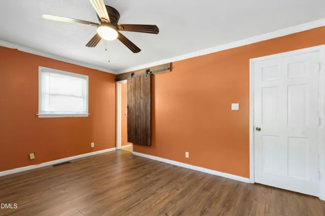 an empty room with wooden floor fan and windows