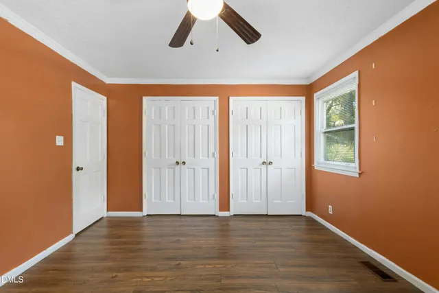 a view of an empty room with wooden floor and window