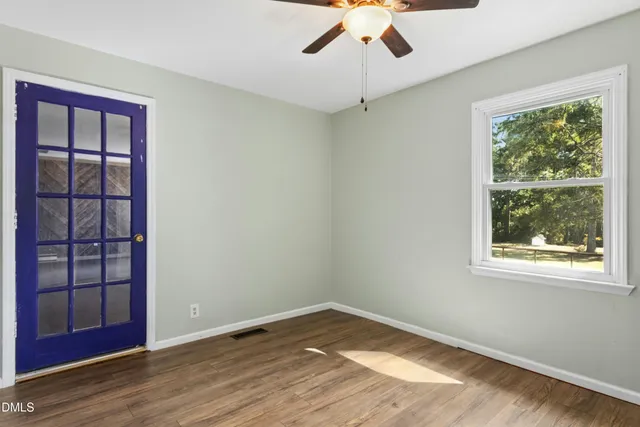 a view of empty room with wooden floor and fan
