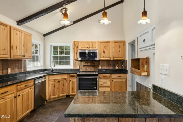 a kitchen with stainless steel appliances granite countertop a stove top oven a sink dishwasher a dining table and chairs with wooden floor