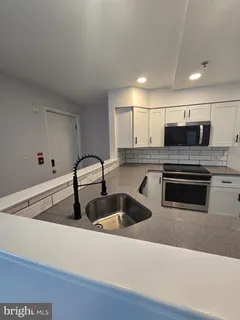 a kitchen with granite countertop a sink and white cabinets