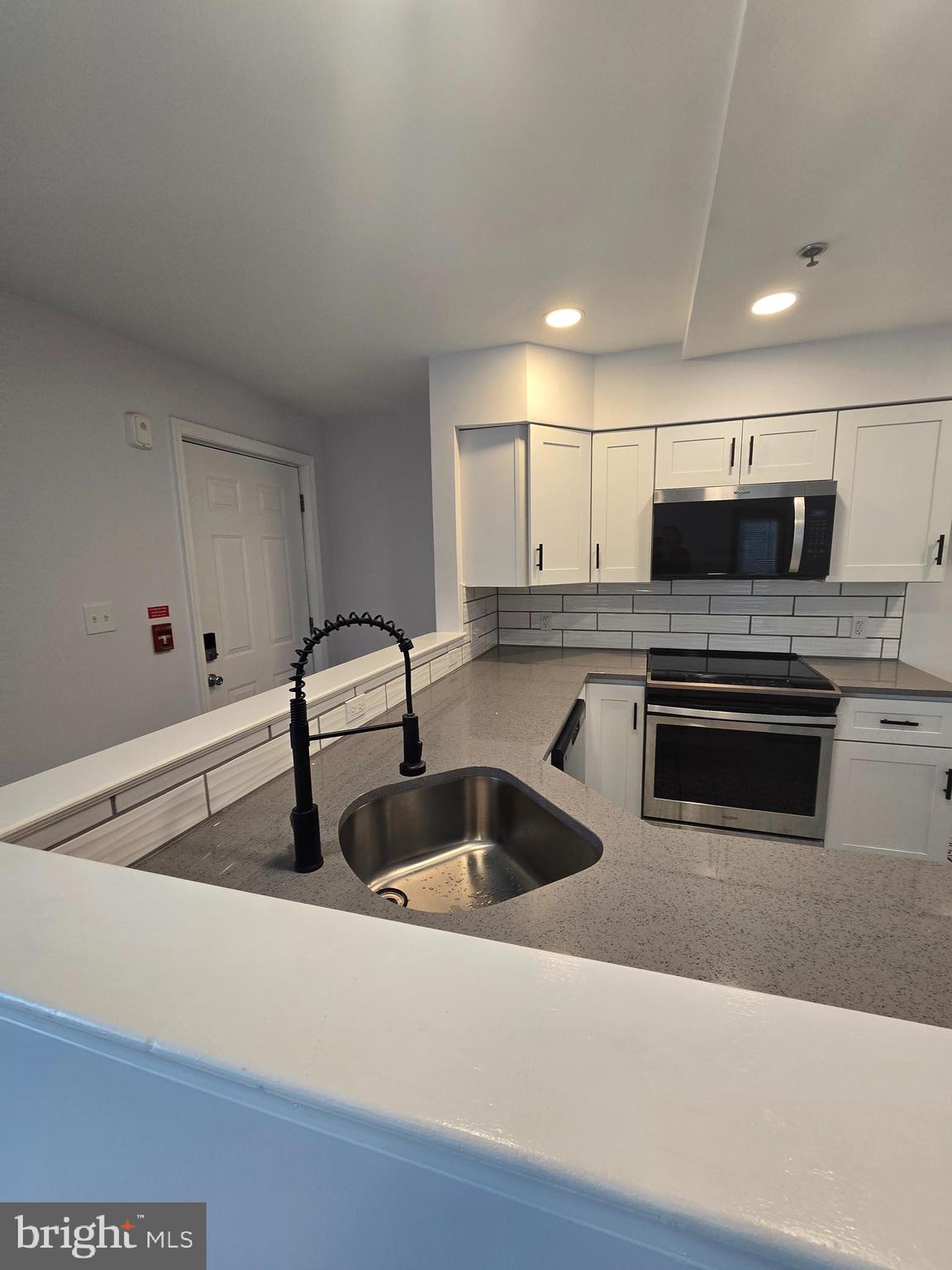 210 Shurs Lane, Unit 4 Philadelphia, PA 19128 - Photo 7 of 24 a kitchen with granite countertop a sink and white cabinets