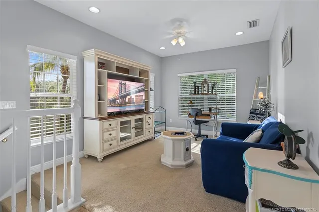 a living room with furniture a flat screen tv and a floor to ceiling window