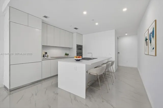 a kitchen with kitchen island a white counter top space cabinets and stainless steel appliances