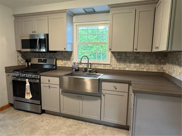 a kitchen with granite countertop white cabinets stainless steel appliances and a sink
