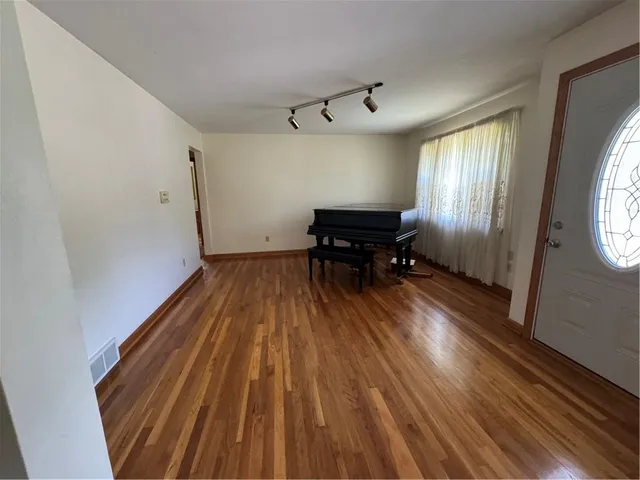 an empty room with wooden floor windows and closet