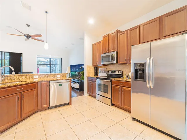 a kitchen with granite countertop a refrigerator stove top oven and sink