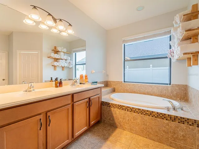 a bathroom with a granite countertop tub a sink and a window