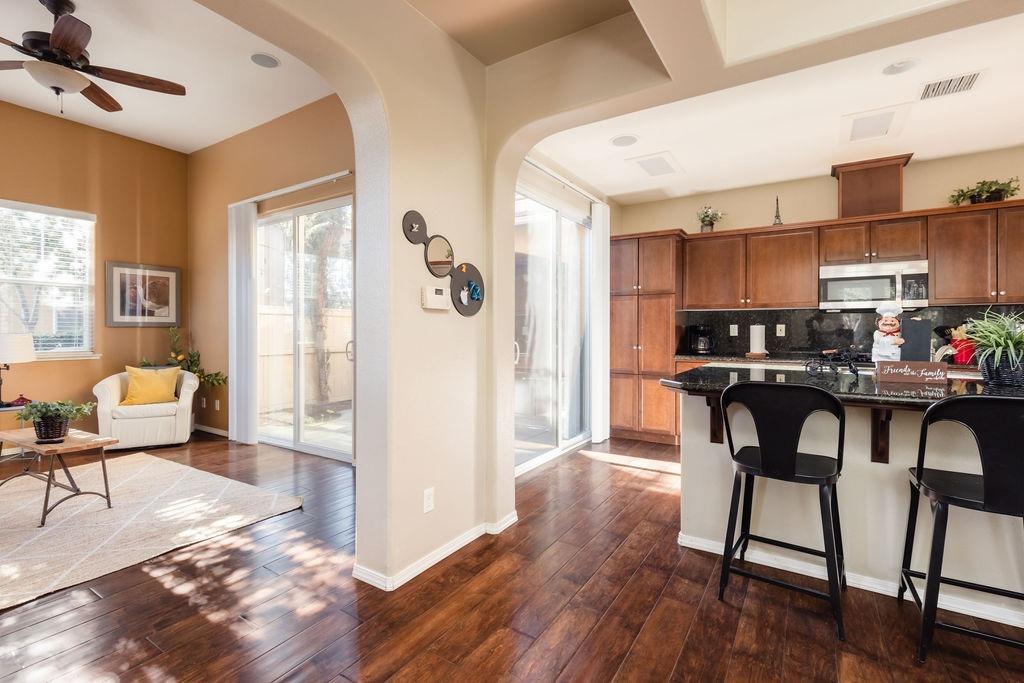 3953 Harlan Ranch Boulevard Clovis, CA 93619 - Photo 1 of 31 a kitchen with granite countertop a refrigerator a stove a dining table and chairs with wooden floor