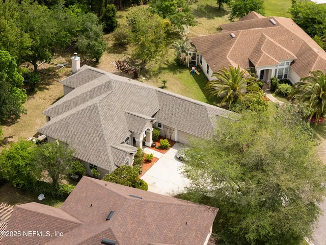 a aerial view of a house with a yard and large trees
