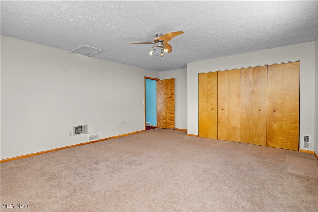 14015 West Lake Road Vermilion, OH 44089 - Photo 29 of 50 Unfurnished bedroom featuring a closet, carpet, a textured ceiling, attic access, and ceiling fan