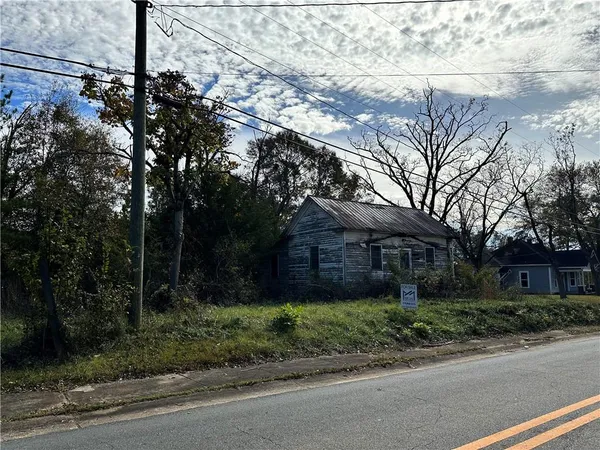 a view of a brick house next to a yard with large trees