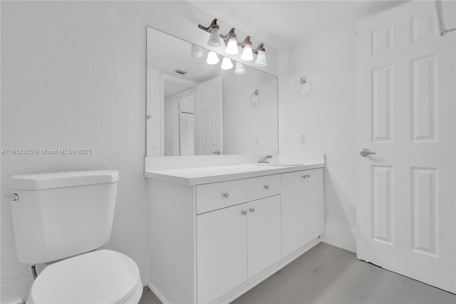 10900 Southwest 104th Street, Unit 121 Miami, FL 33176 - Photo 16 of 34 a bathroom with a toilet a sink a mirror and vanity