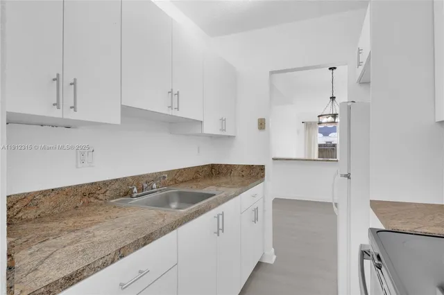 a kitchen with granite countertop white cabinets and a sink