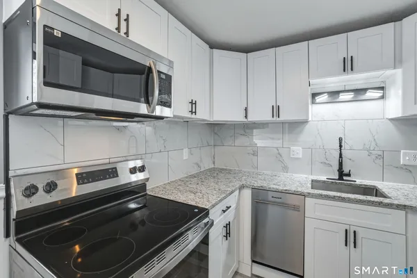 a kitchen with granite countertop a stove microwave and sink
