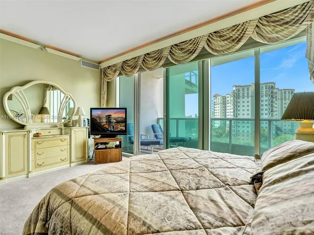 a bedroom with a bed a large window and flat screen tv