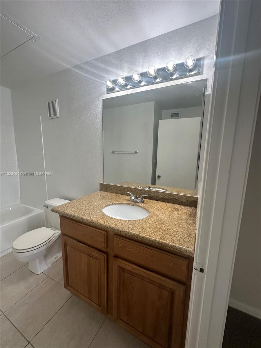 a bathroom with a granite countertop sink a toilet and a mirror