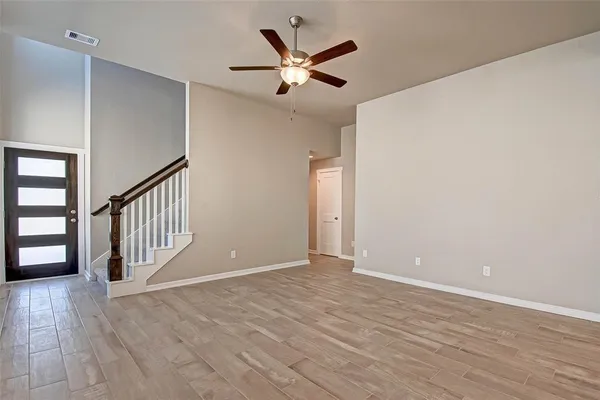 a view of an empty room with window and wooden floor