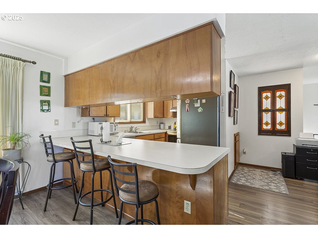 14850 Northeast Rose Parkway, Unit 67A Portland, OR 97230 - Photo 13 of 33 a dining hall with stainless steel appliances kitchen island granite countertop a table chairs and a refrigerator